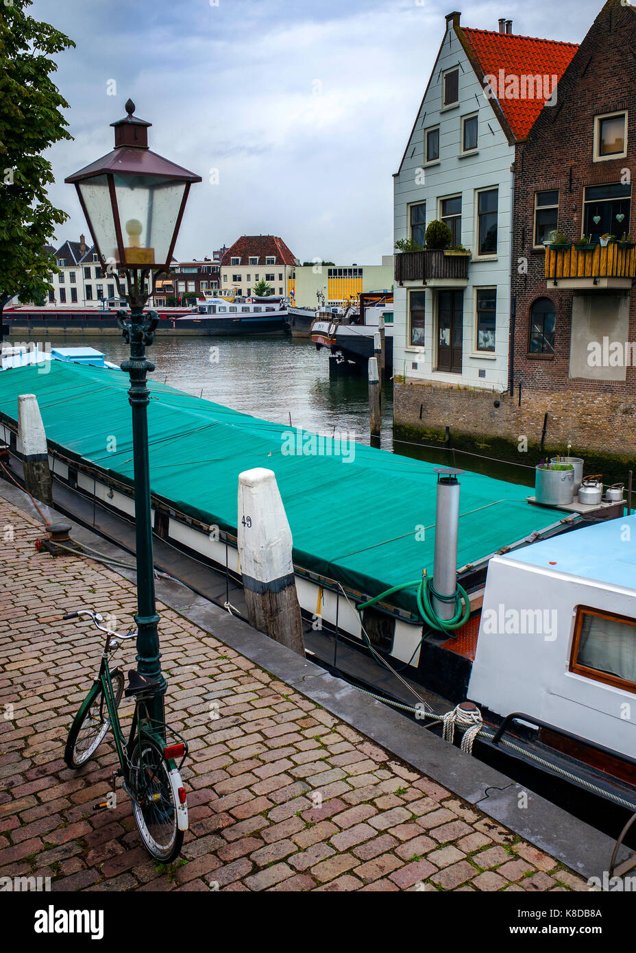 vélo en lampadaire sur un chemin pavé à côté de la barge amarrée sur la rivière de Dordrecht, pays-Bas Banque D'Images