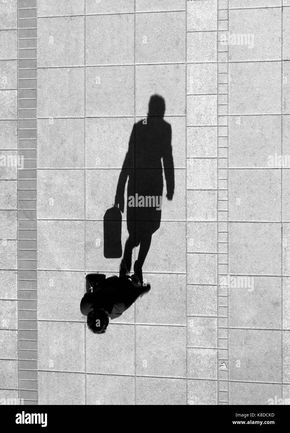 Une femme , la marche et tenant un sac , ombre sur le trottoir ville propre d'en haut en noir et blanc Banque D'Images