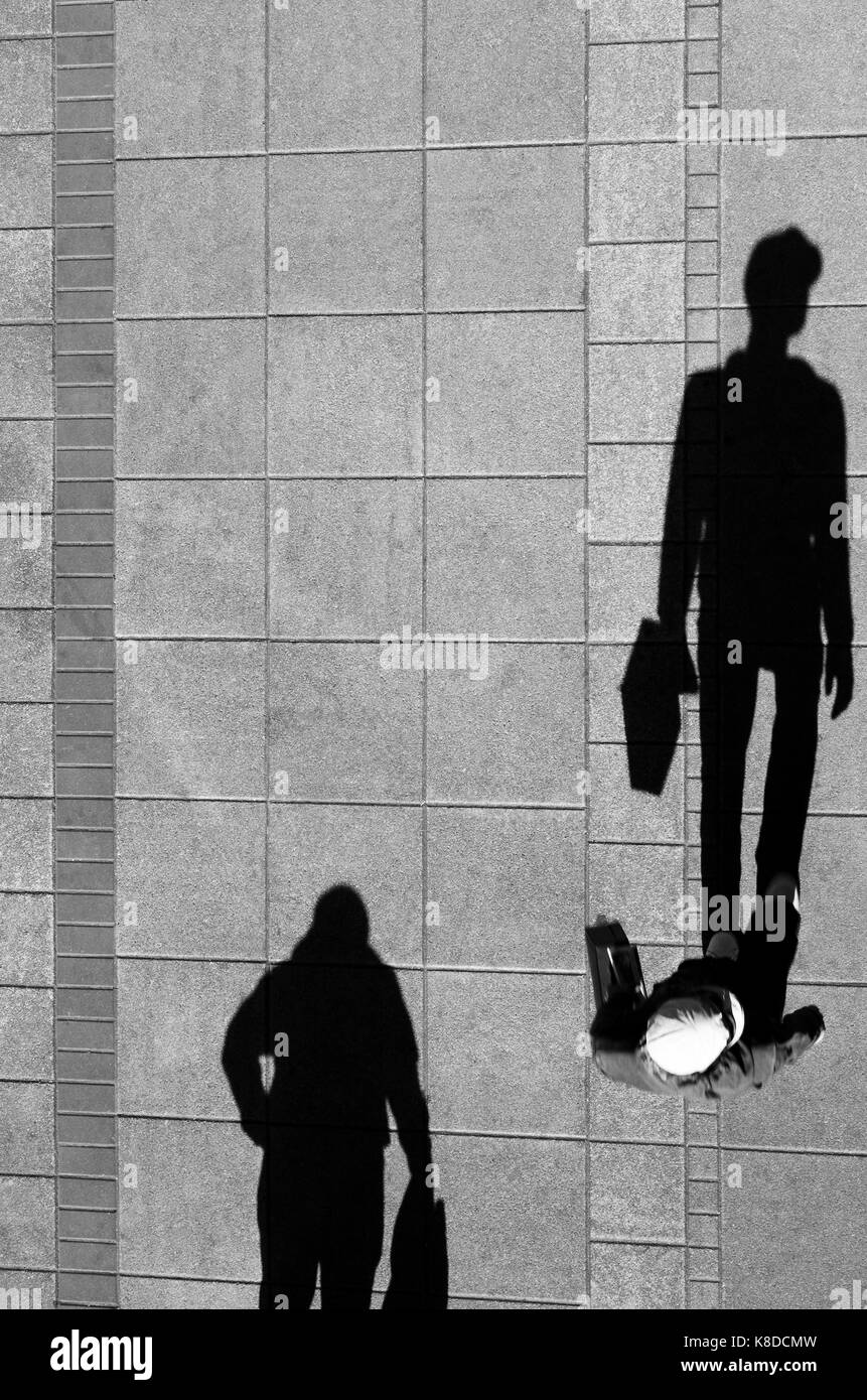 Deux hommes , walking and holding sacs , ombre sur le trottoir ville propre d'en haut en noir et blanc Banque D'Images
