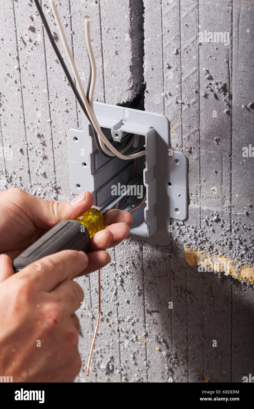 Un électricien protéger une boîte utilitaire électrique à l'aide d'un tournevis plat dans des coffrages de béton isolés dans l'Ontario, Canada. Banque D'Images