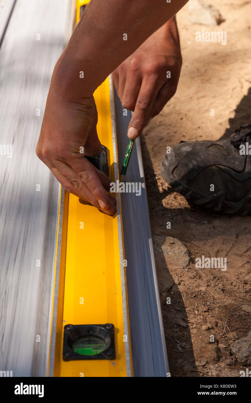 Un travailleur de la construction de revêtement de vinyle de marquage à l'aide d'un crayon et d'un niveau de charpentier comme un bord droit de l'Ontario, Canada. Banque D'Images