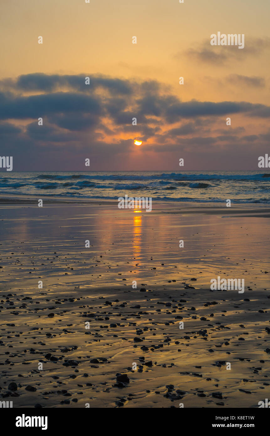 Belle plage coucher du soleil à l'atmosphère avec des réflexions et plack cailloux, l'autre à Sidi Ifni, Maroc, afrique du nord. Banque D'Images
