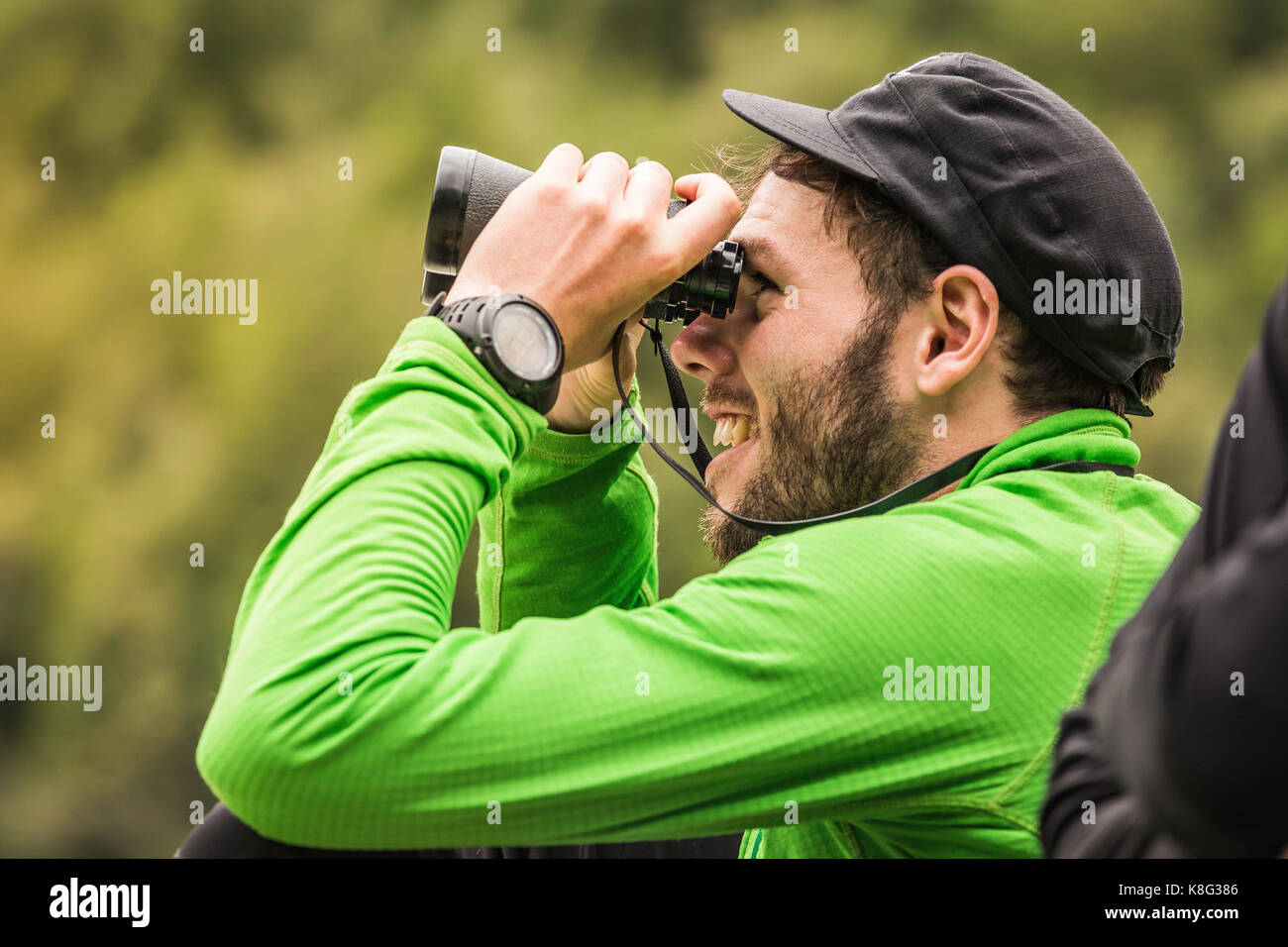 Young male backpacker regardant à travers les jumelles dans le parc national queulat, Chili Banque D'Images