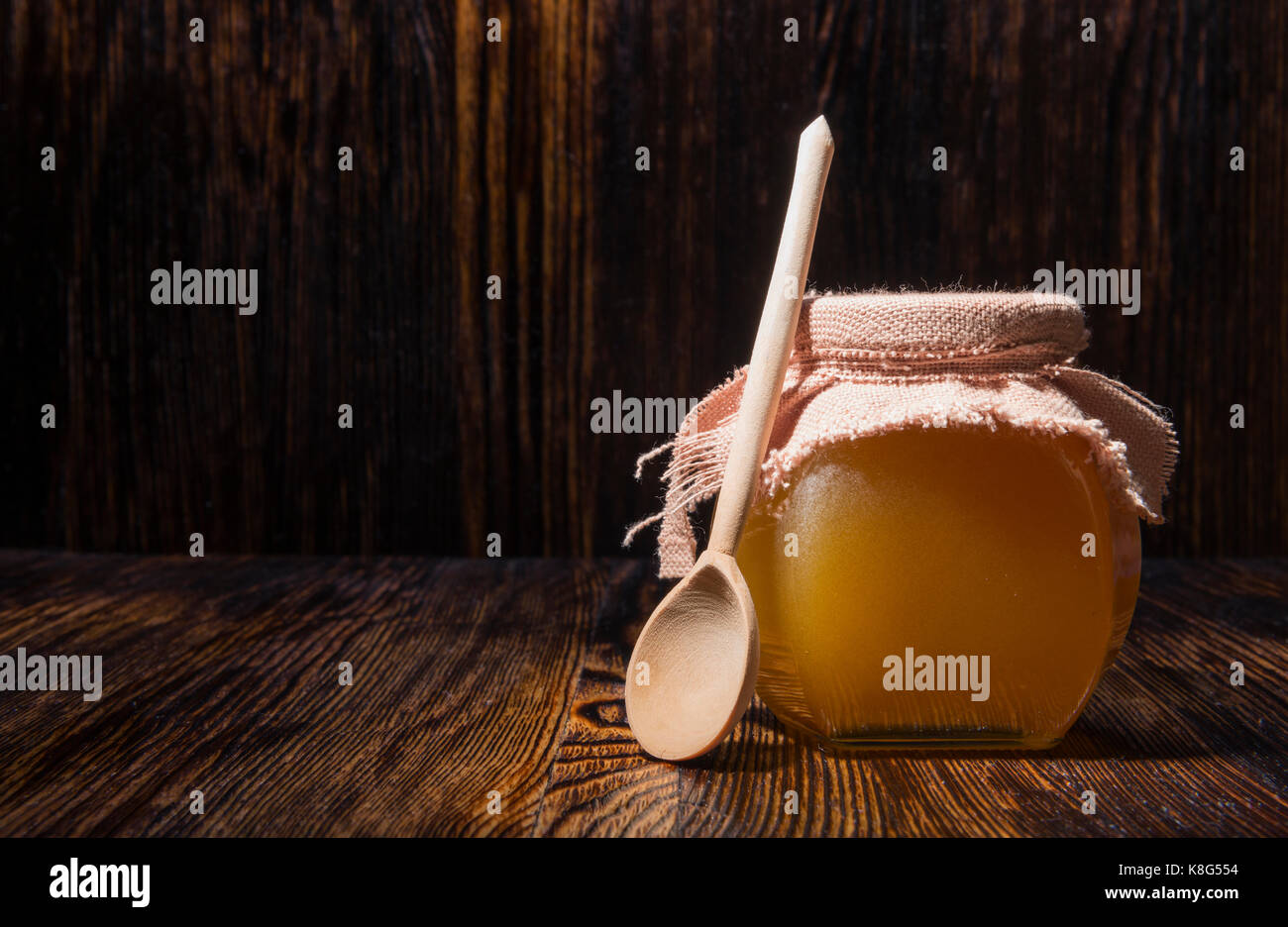 Pot de miel et une cuillère sur un fond de bois Banque D'Images