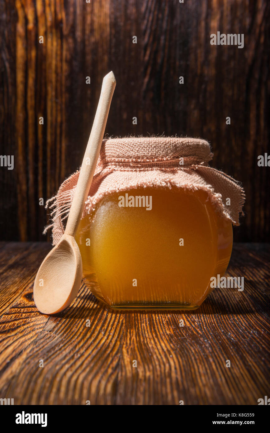 Pot de miel et une cuillère sur un fond de bois Banque D'Images