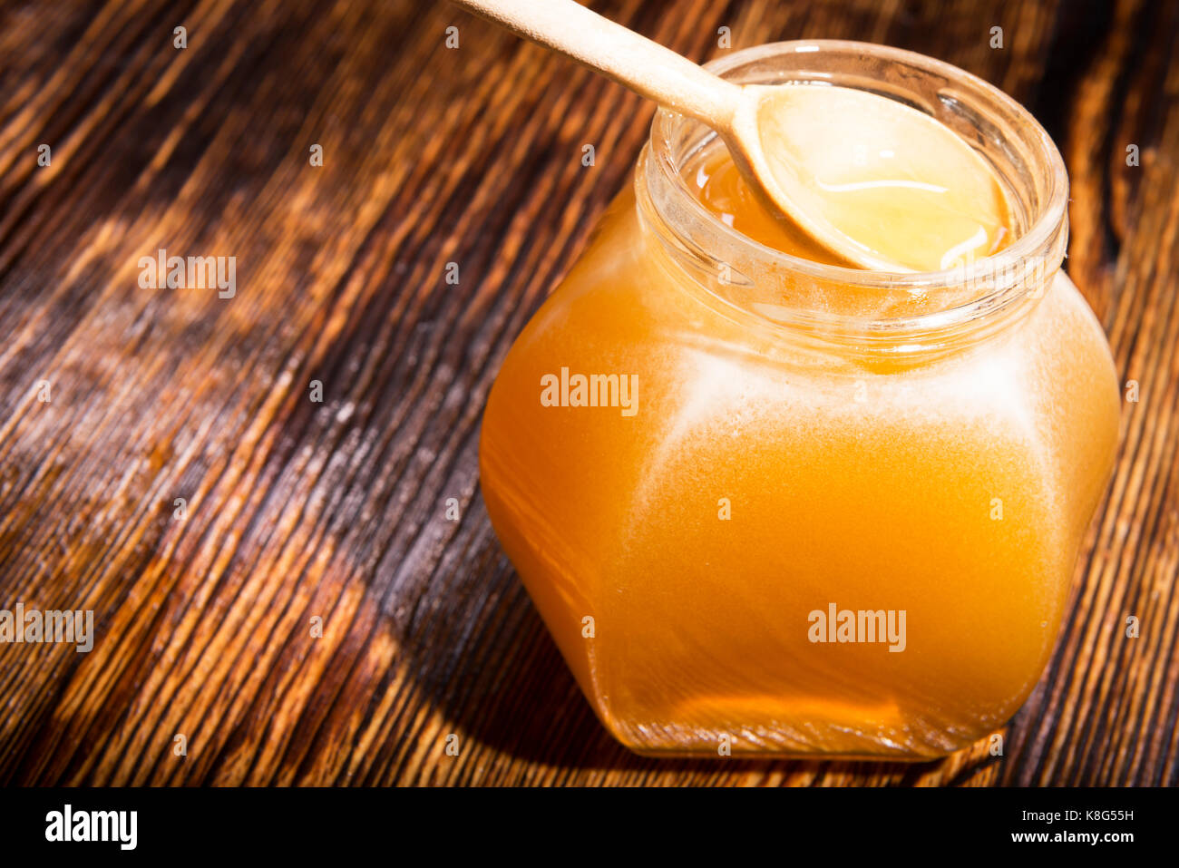 Pot de miel et une cuillère sur un fond de bois Banque D'Images
