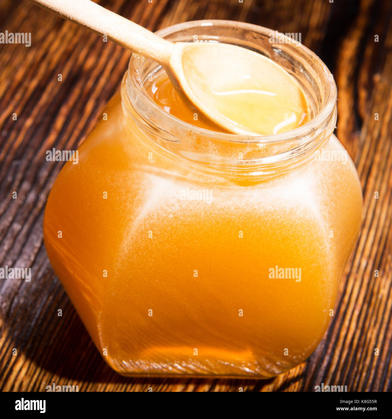 Pot de miel et une cuillère sur un fond de bois Banque D'Images