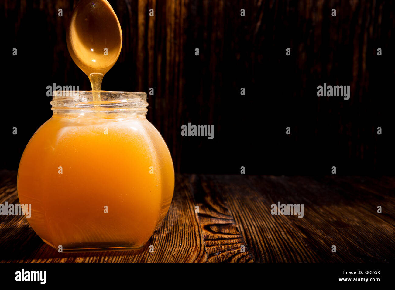 Pot de miel et une cuillère sur un fond de bois Banque D'Images