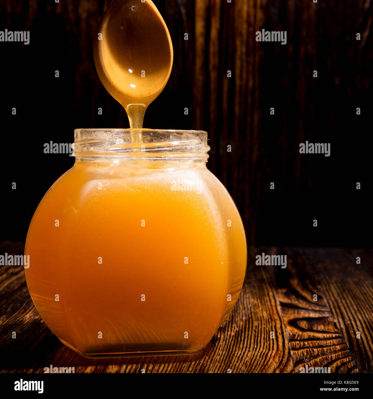 Pot de miel et une cuillère sur un fond de bois Banque D'Images