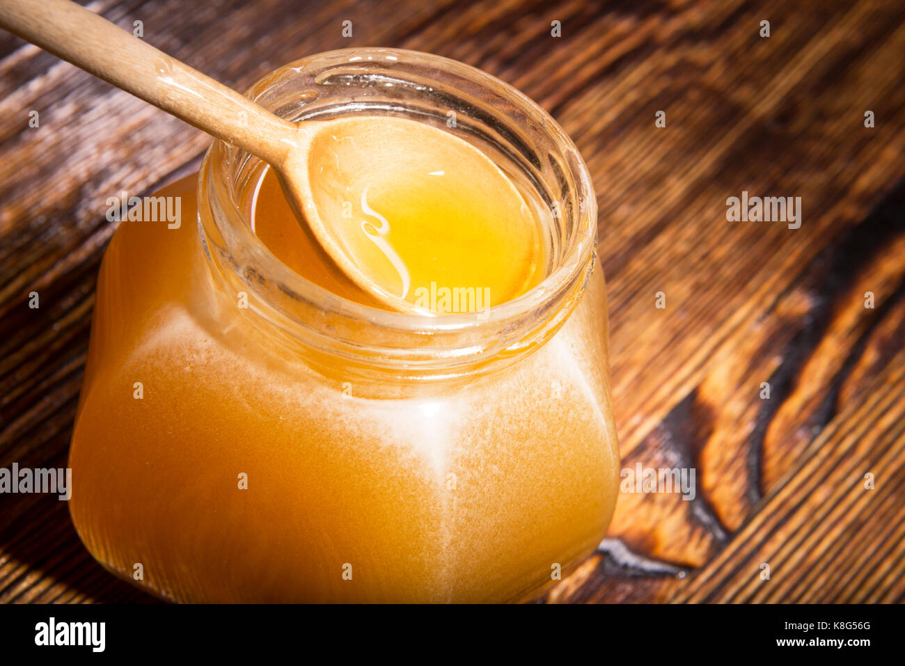 Pot de miel et une cuillère sur un fond de bois Banque D'Images