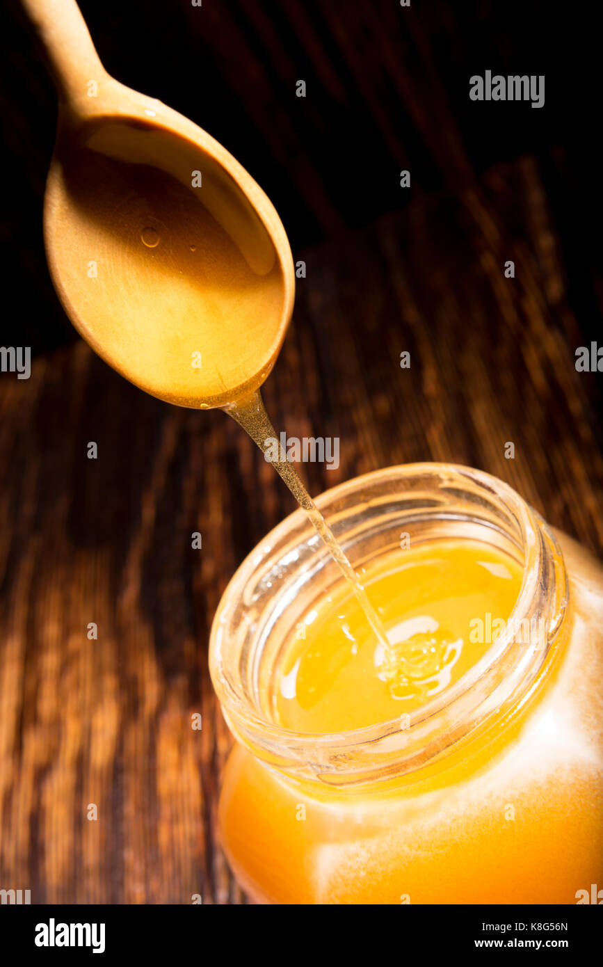 Pot de miel et une cuillère sur un fond de bois Banque D'Images