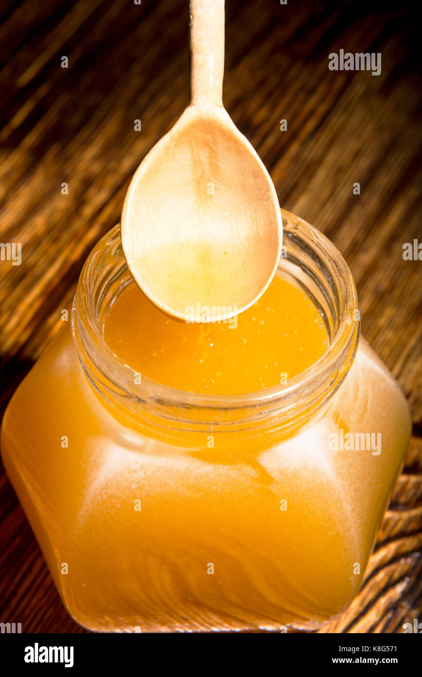 Pot de miel et une cuillère sur un fond de bois Banque D'Images