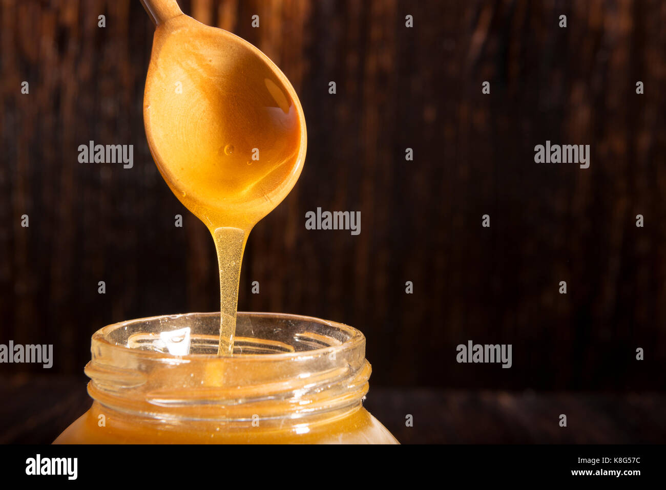 Pot de miel et une cuillère sur un fond de bois Banque D'Images