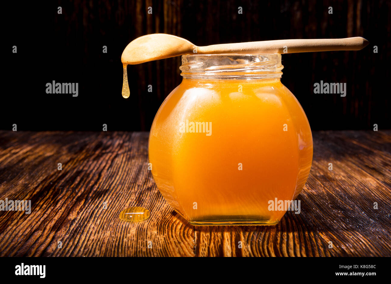 Pot de miel et une cuillère sur un fond de bois Banque D'Images