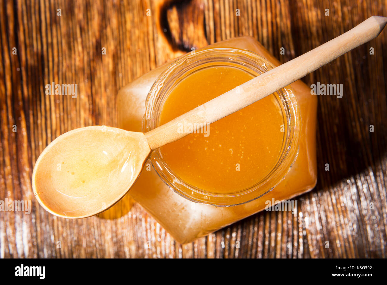 Pot de miel et une cuillère sur un fond de bois Banque D'Images