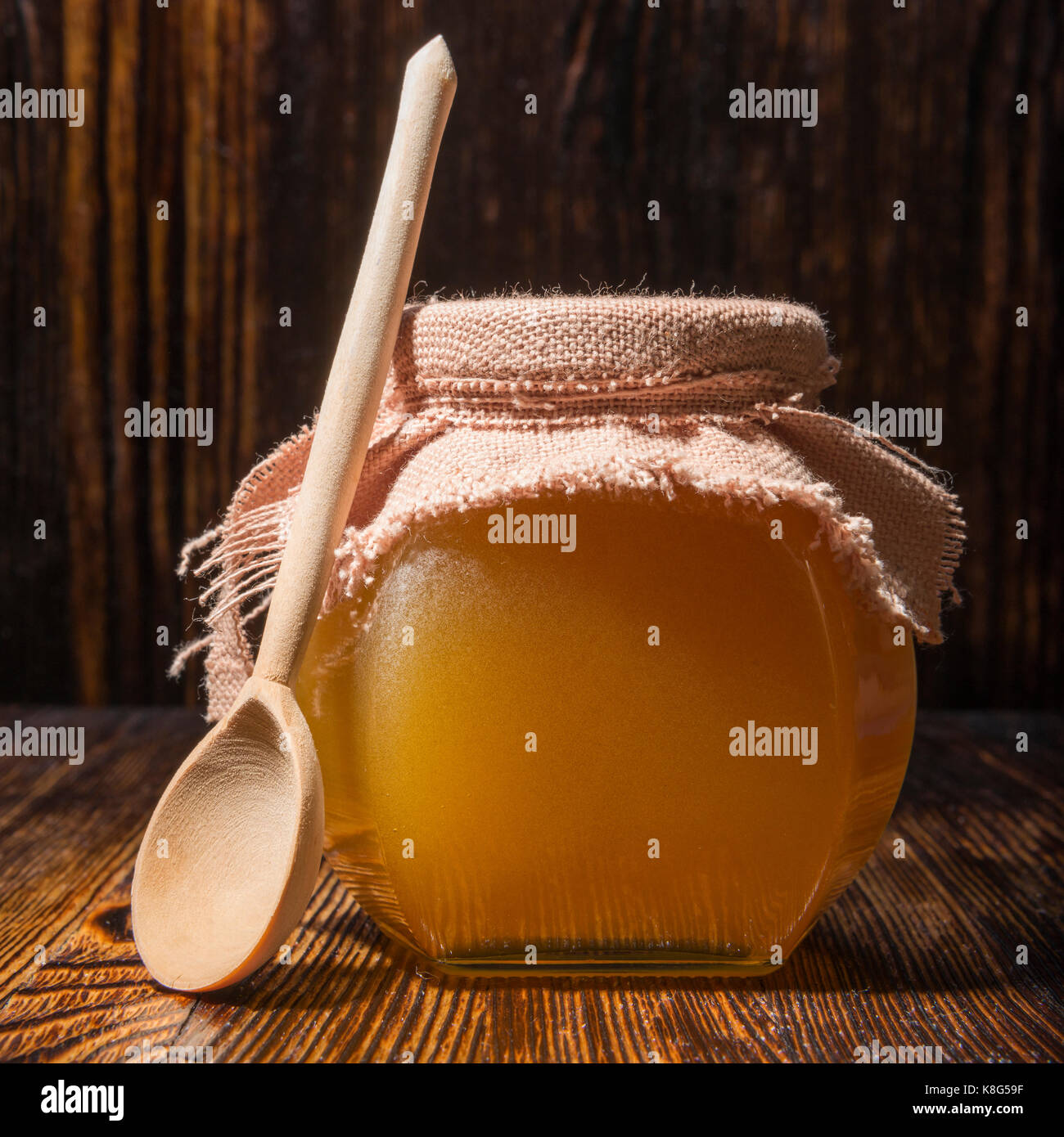 Pot de miel et une cuillère sur un fond de bois Banque D'Images