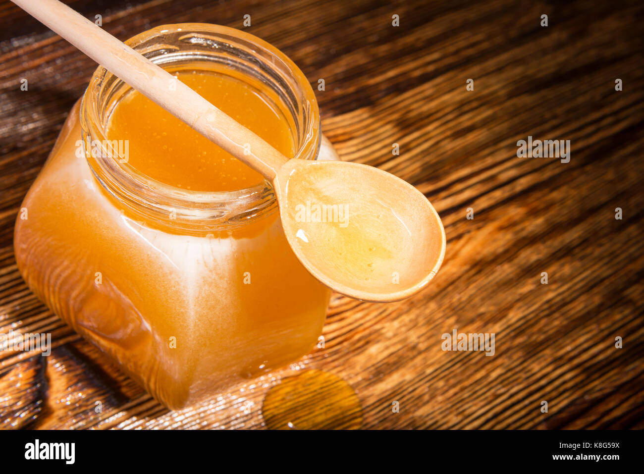 Pot de miel et une cuillère sur un fond de bois Banque D'Images
