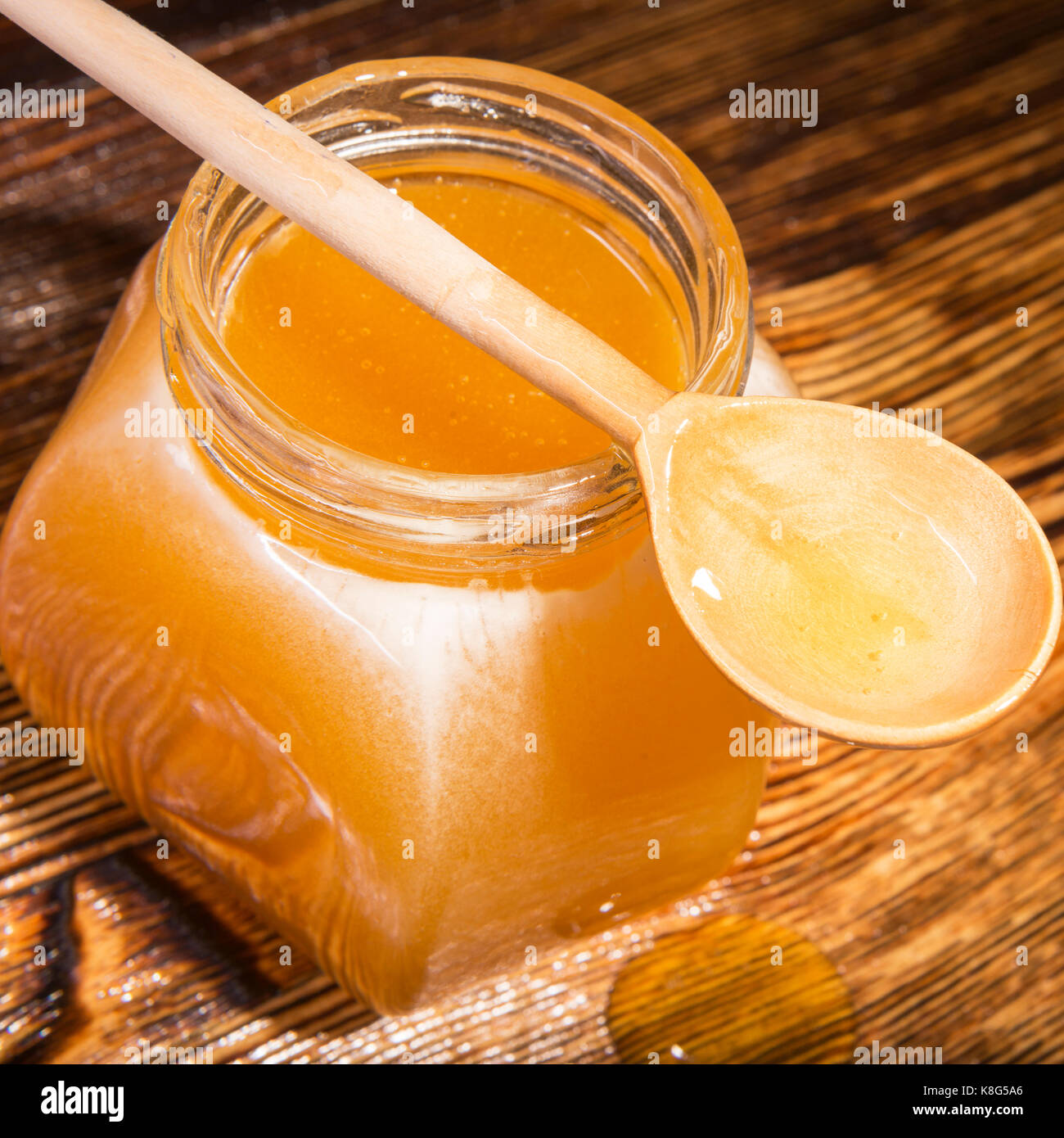 Pot de miel et une cuillère sur un fond de bois Banque D'Images