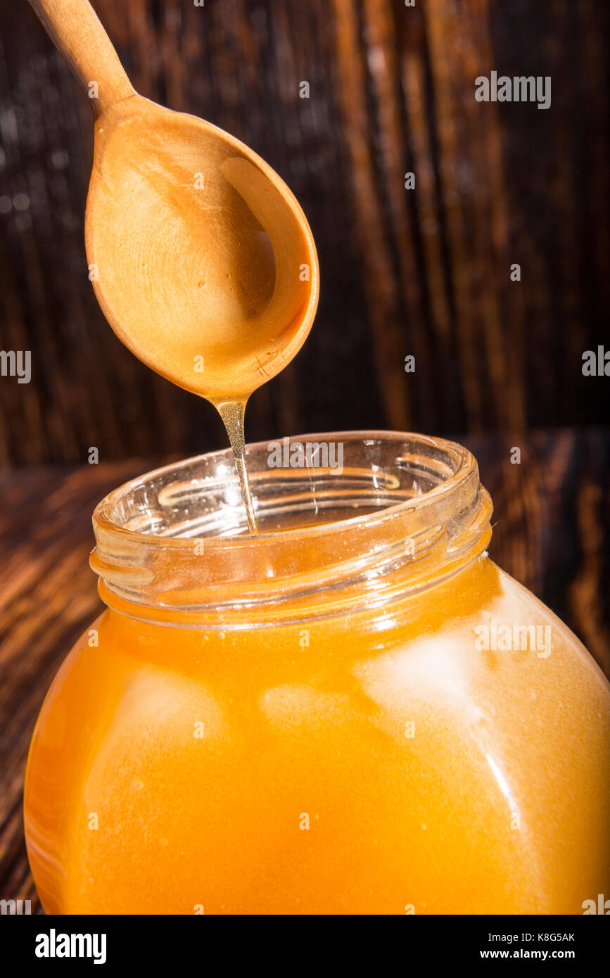 Pot de miel et une cuillère sur un fond de bois Banque D'Images