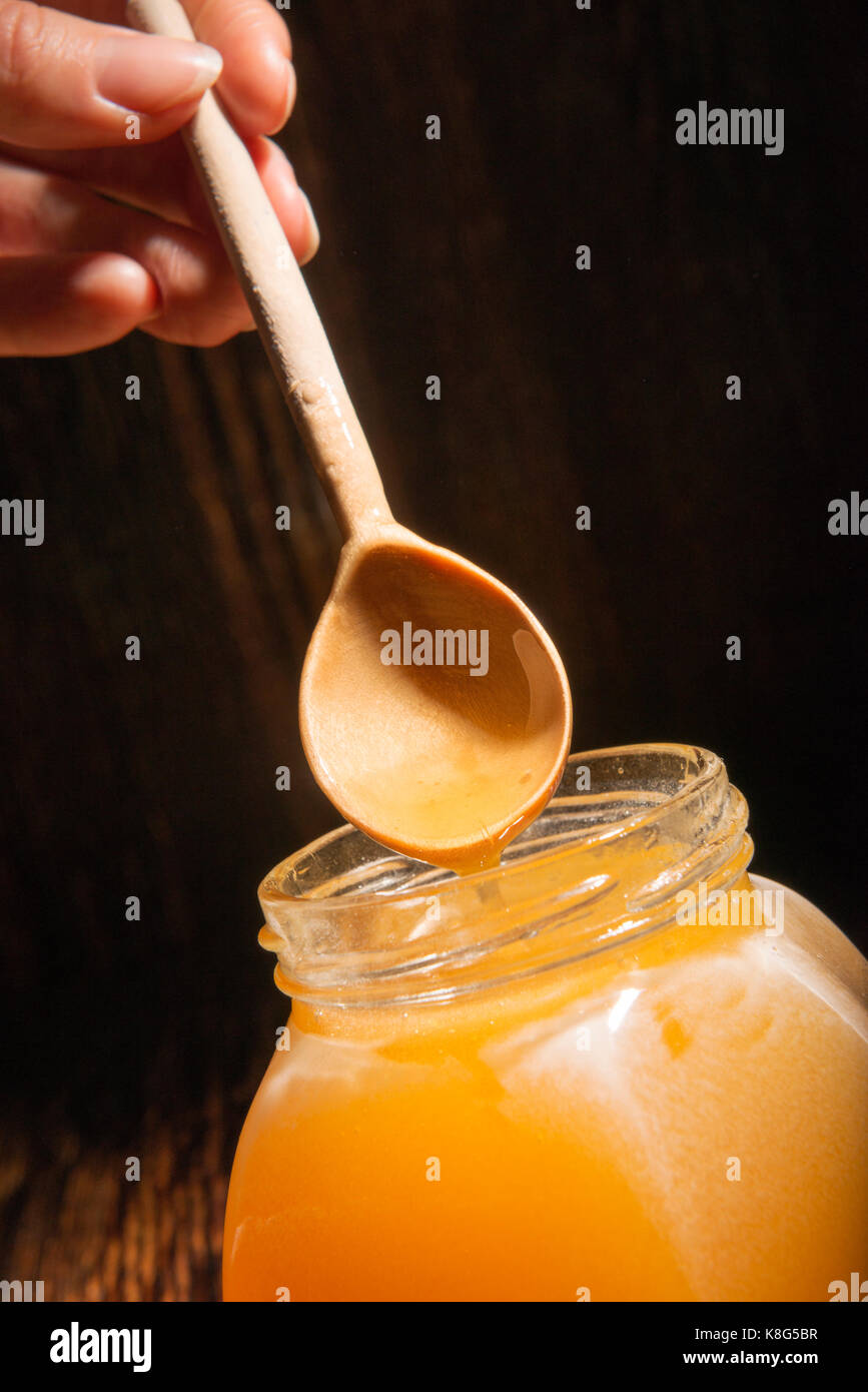 Pot de miel et une cuillère sur un fond de bois Banque D'Images