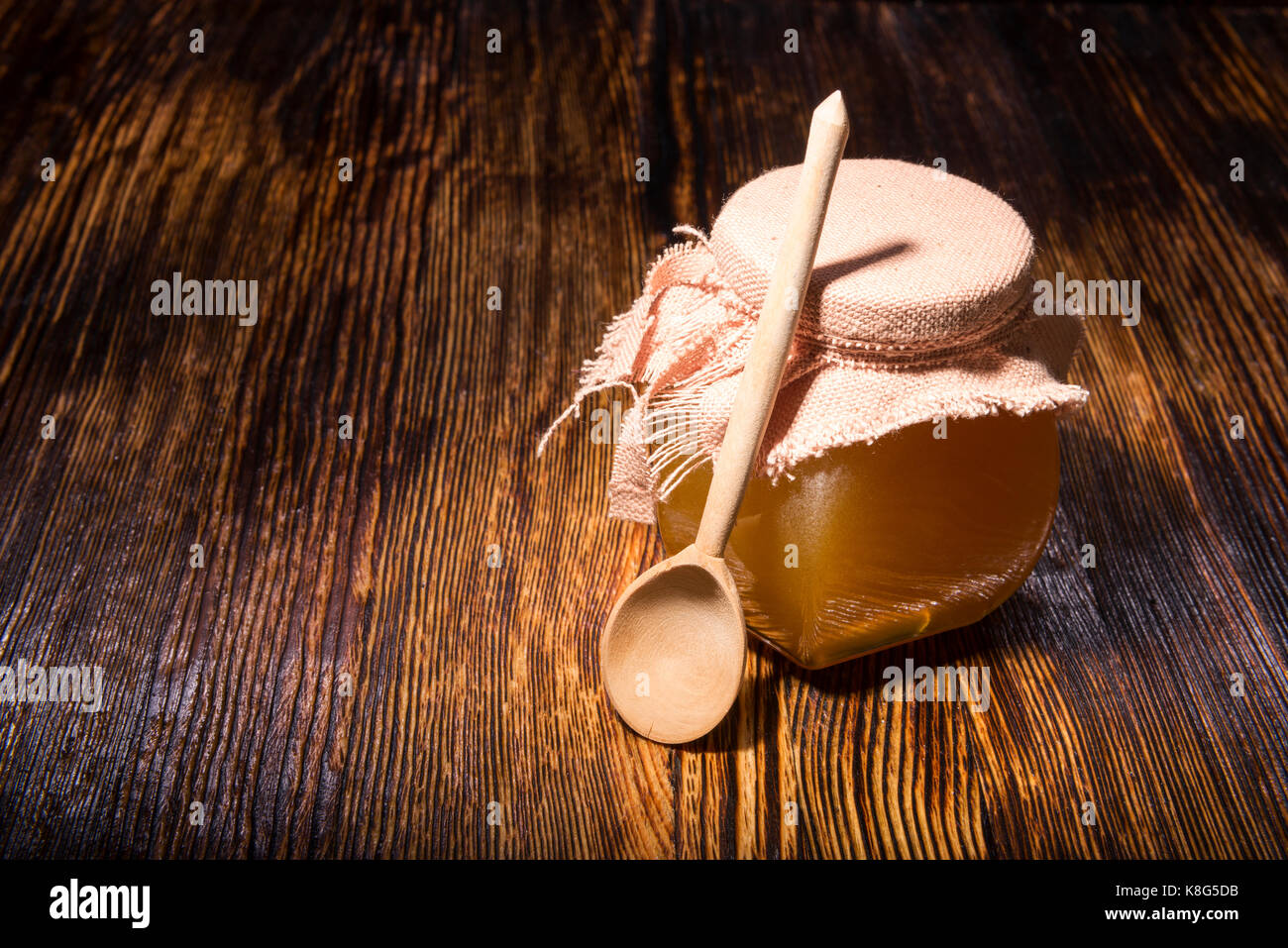 Pot de miel et une cuillère sur un fond de bois Banque D'Images
