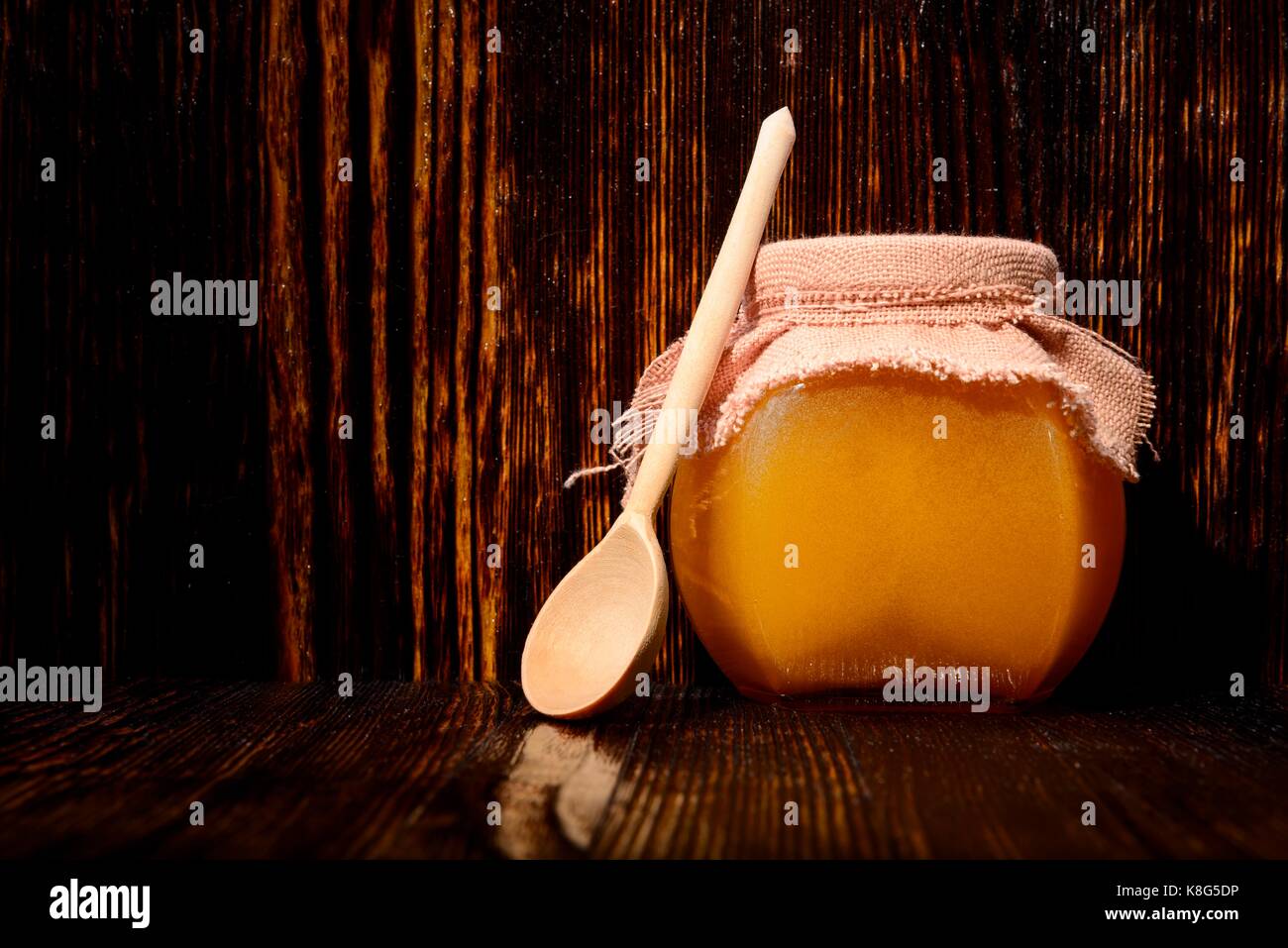 Pot de miel et une cuillère sur un fond de bois Banque D'Images