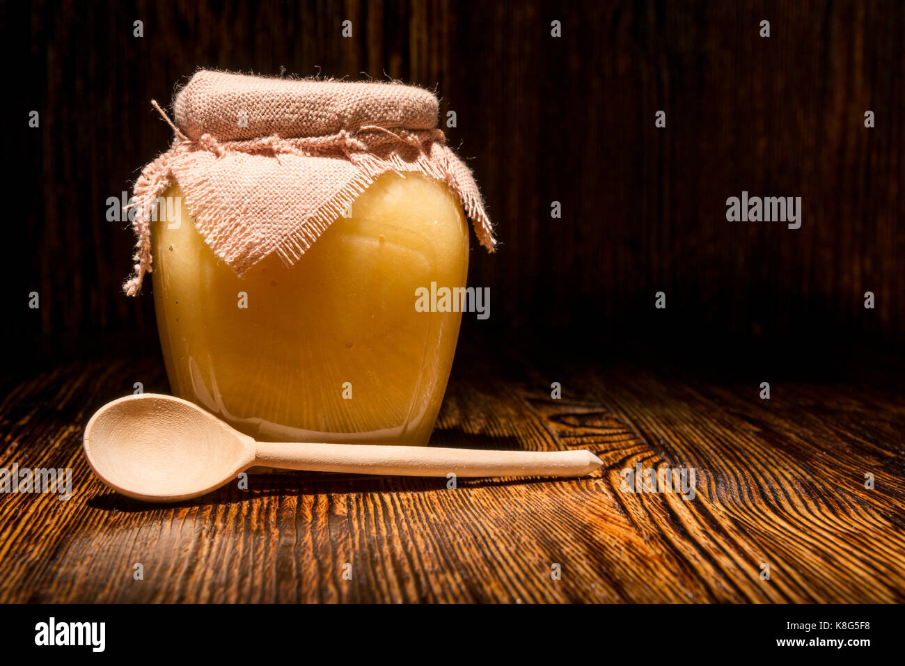 Pot de miel et une cuillère sur un fond de bois Banque D'Images