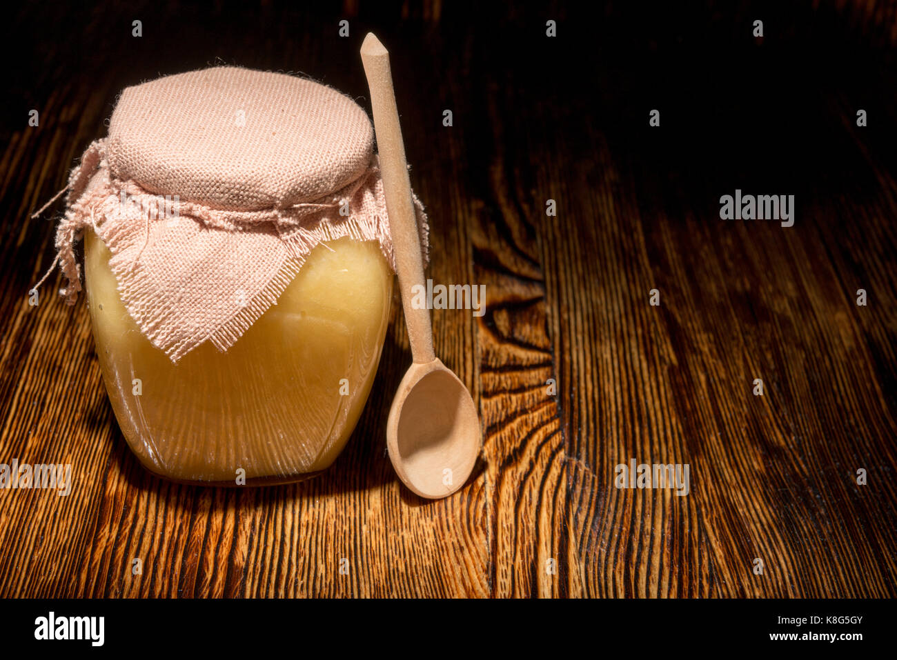Pot de miel et une cuillère sur un fond de bois Banque D'Images