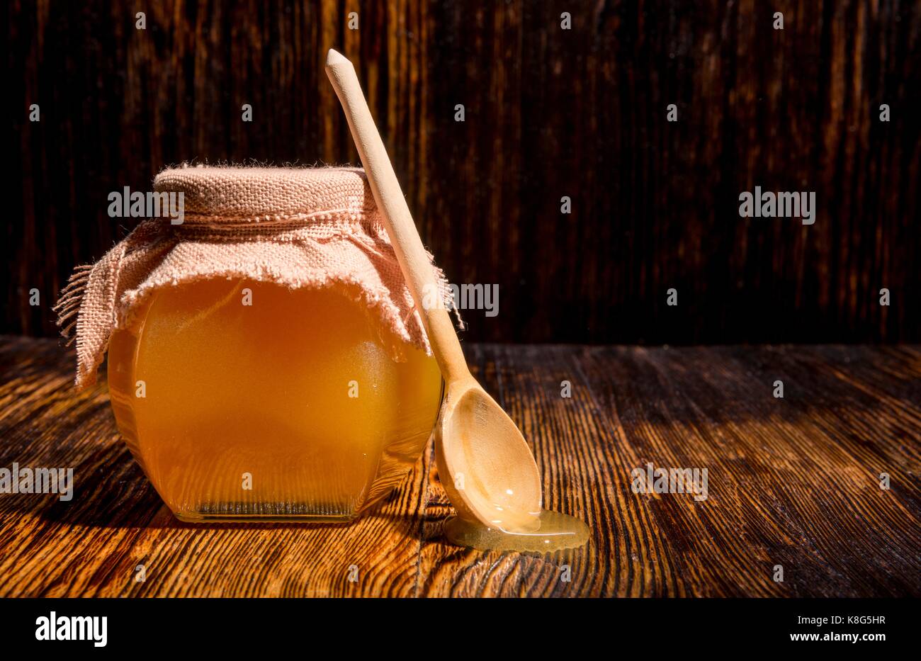 Pot de miel et une cuillère sur un fond de bois Banque D'Images