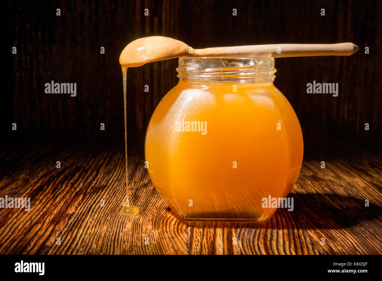 Pot de miel et une cuillère sur un fond de bois Banque D'Images