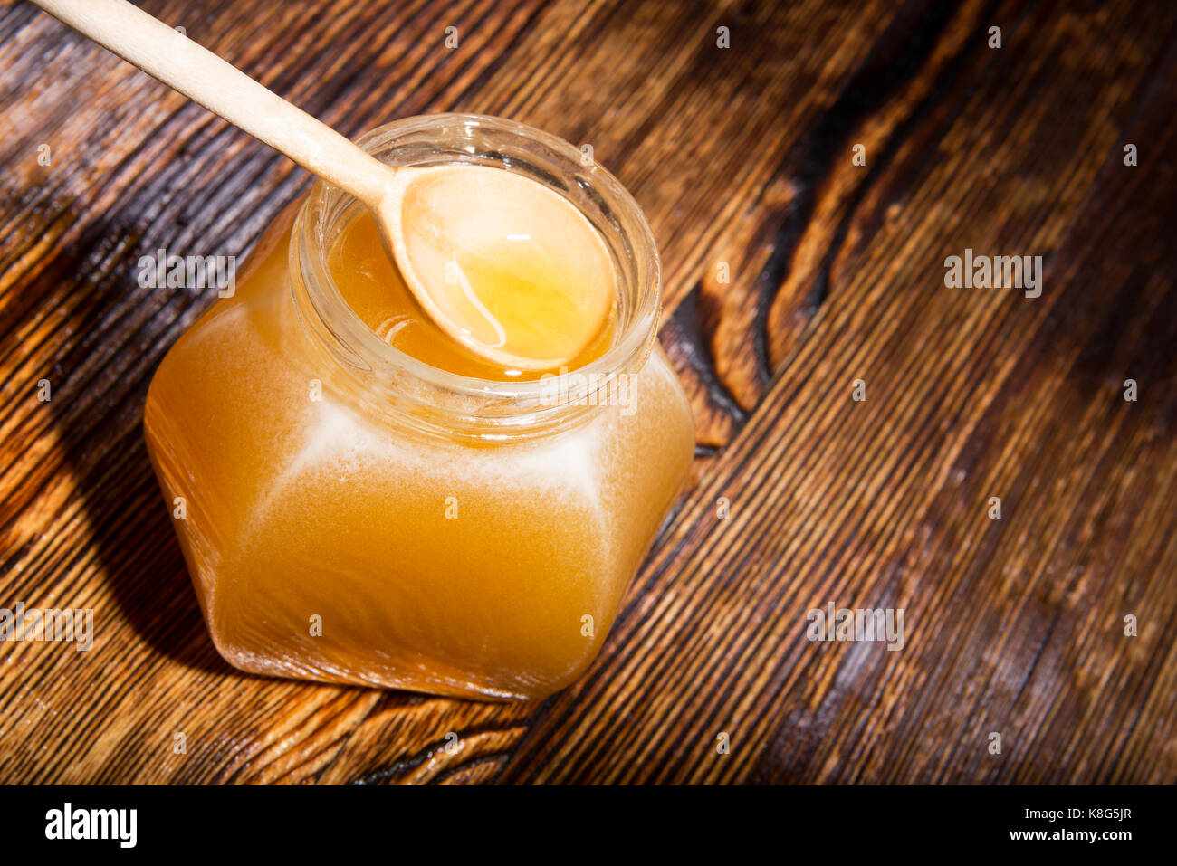 Pot de miel et une cuillère sur un fond de bois Banque D'Images
