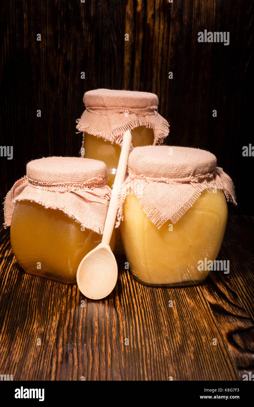 Trois pots de miel et une cuillère sur un fond de bois Banque D'Images