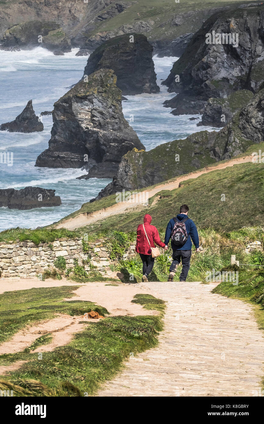 Bedruthan Steps - un couple marche main dans la main sur le South West Coast Path au Bedruthan Steps sur la côte nord des Cornouailles. Banque D'Images