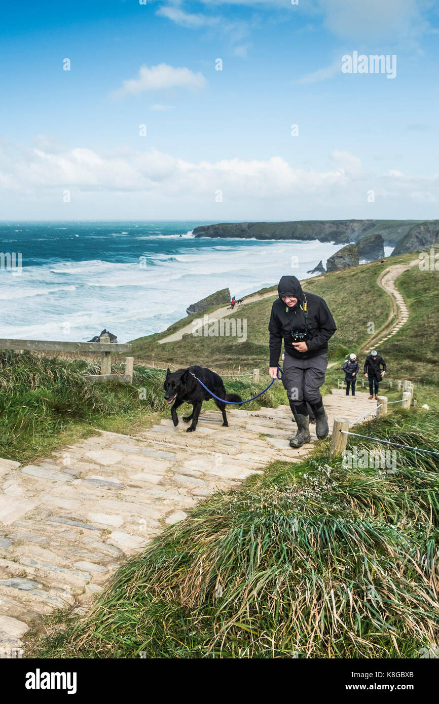 Bedruthan Steps - une marchette et son chien grimper le sentier raide au Bedruthan Steps sur la côte nord des Cornouailles. Banque D'Images