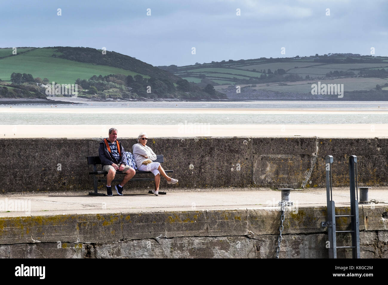 Padstow Harbour - un couple assis sur un banc et profiter du soleil dans le port à Padstow sur la côte nord des Cornouailles. Banque D'Images