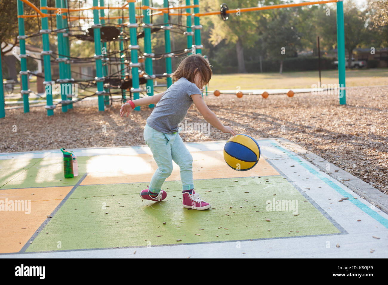Basket-ball bouncing Girl in playground Banque D'Images