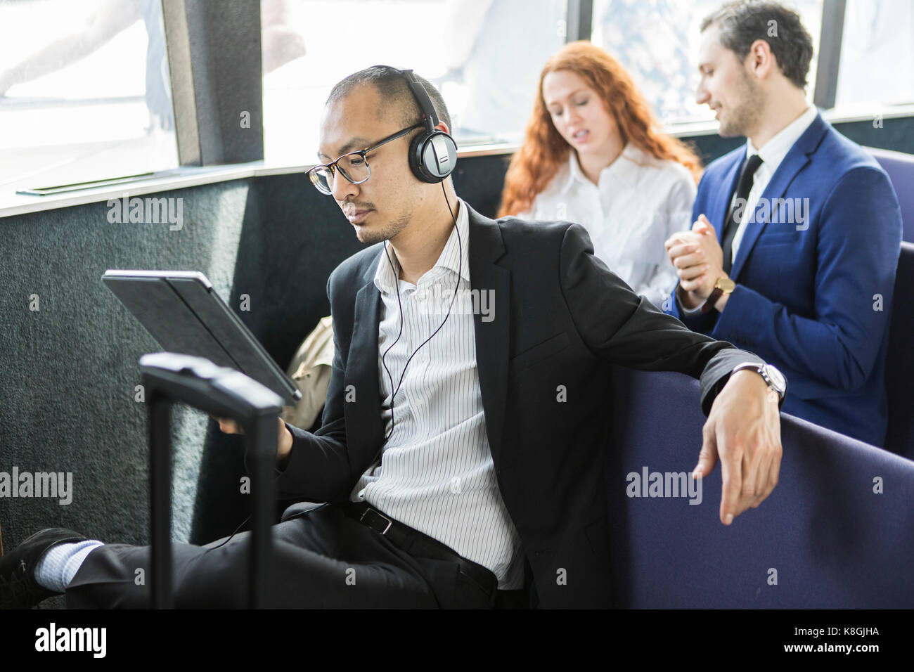 Businessman listening to headphones looking at digital tablet sur le traversier pour passagers Banque D'Images