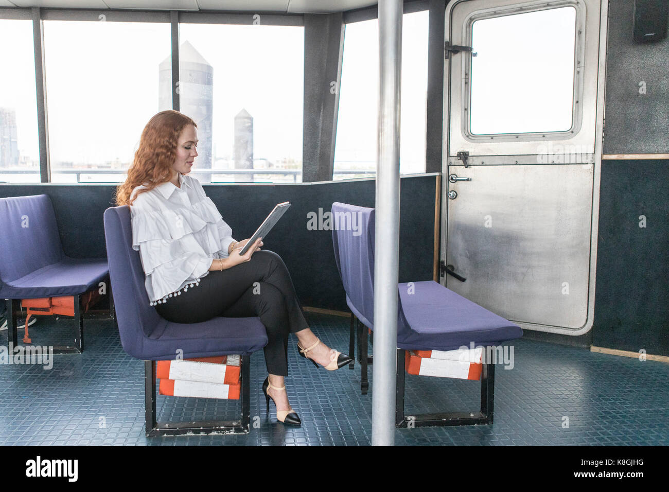 Les jeunes élégantes businesswoman looking at digital tablet sur le traversier pour passagers Banque D'Images