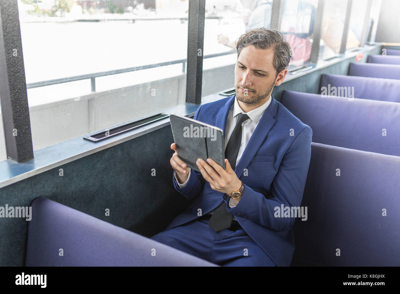 Young businessman looking at digital tablet sur le traversier pour passagers Banque D'Images