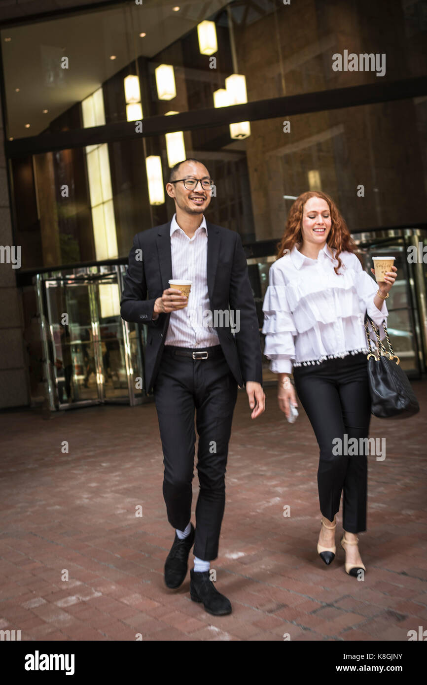 Young businesswoman et l'homme avec du café à emporter en flânant sur trottoir, New York, USA Banque D'Images