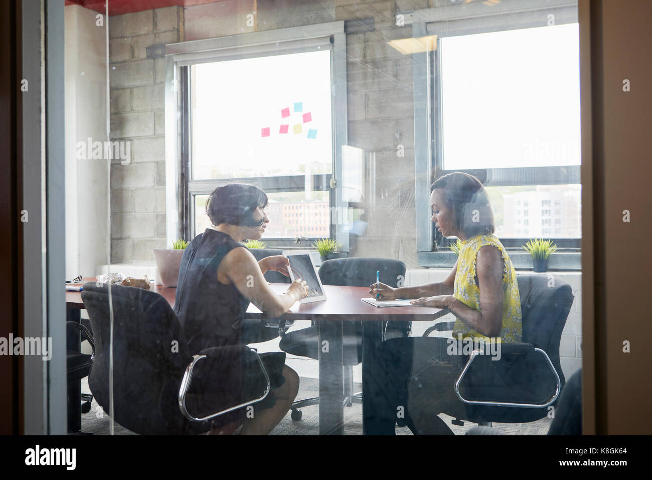 Deux femmes travaillant ensemble dans la salle de réunion, brainstorming, using digital tablet Banque D'Images