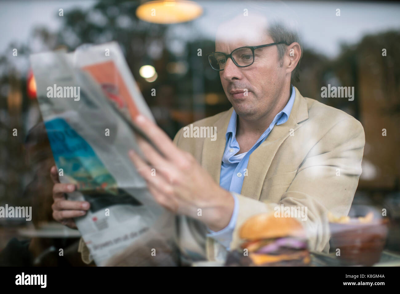 Man reading newspaper in coffee shop Banque D'Images