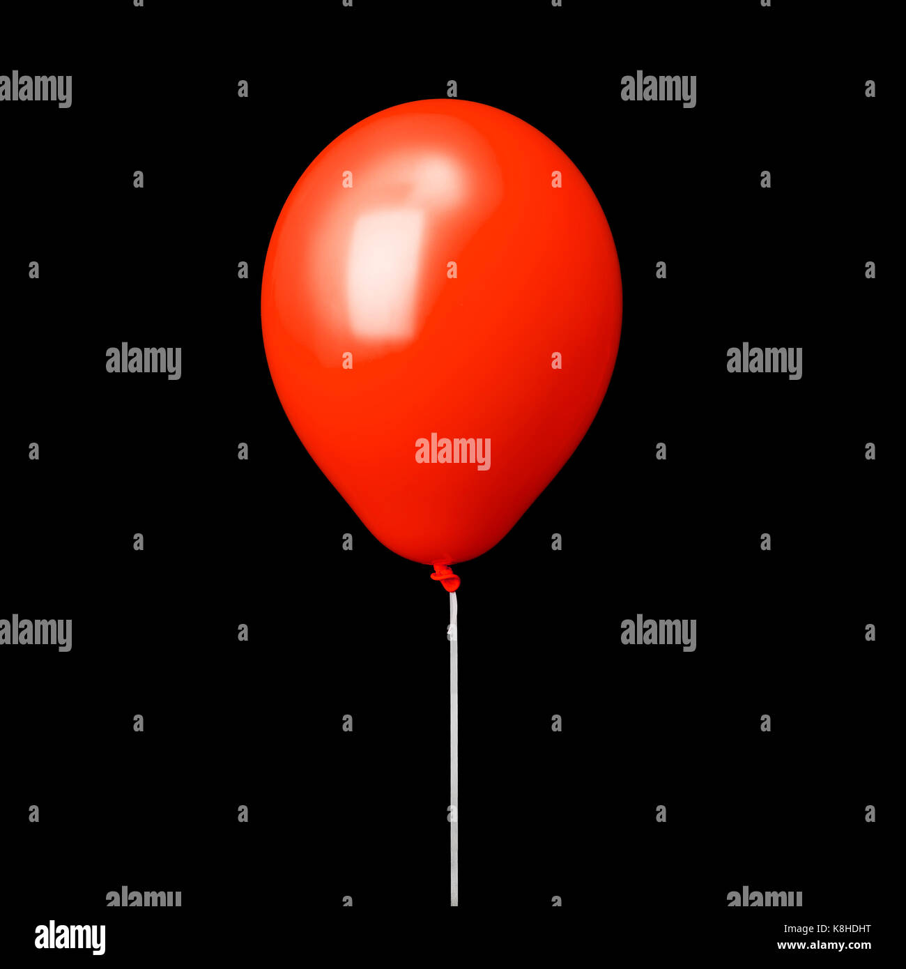 Ballon rouge sur ruban blanc isolé sur fond noir Banque D'Images