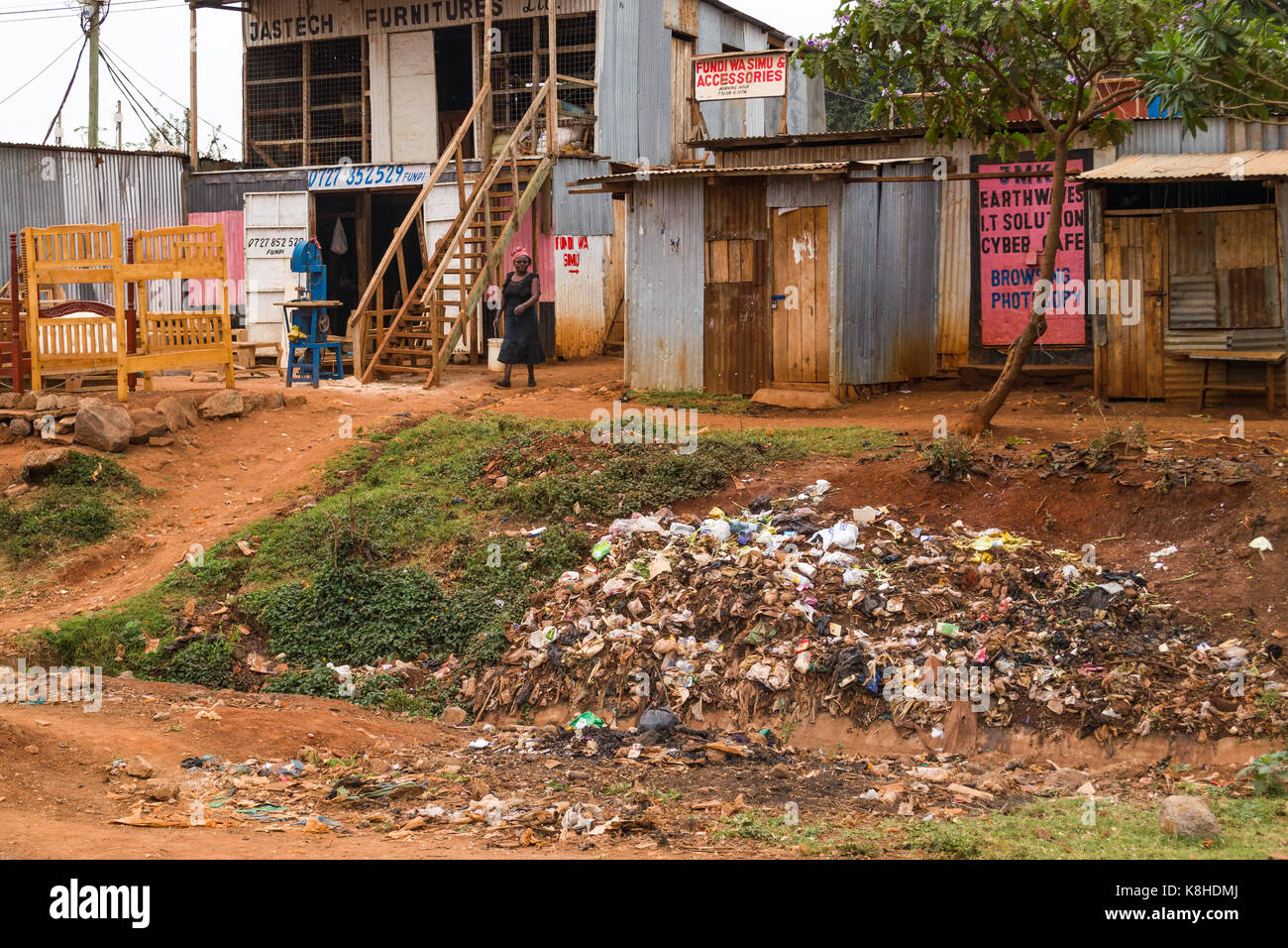 Des cabanes et des capacités routières avec des meubles à l'extérieur, des déchets d'ordures en premier plan, au Kenya Banque D'Images