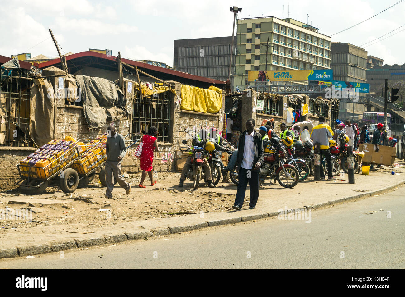La chaussée routière avec des gens, les cavaliers boda boda en moto, et d'attente des magasins et bâtiments en arrière-plan, Nairobi, Kenya Banque D'Images