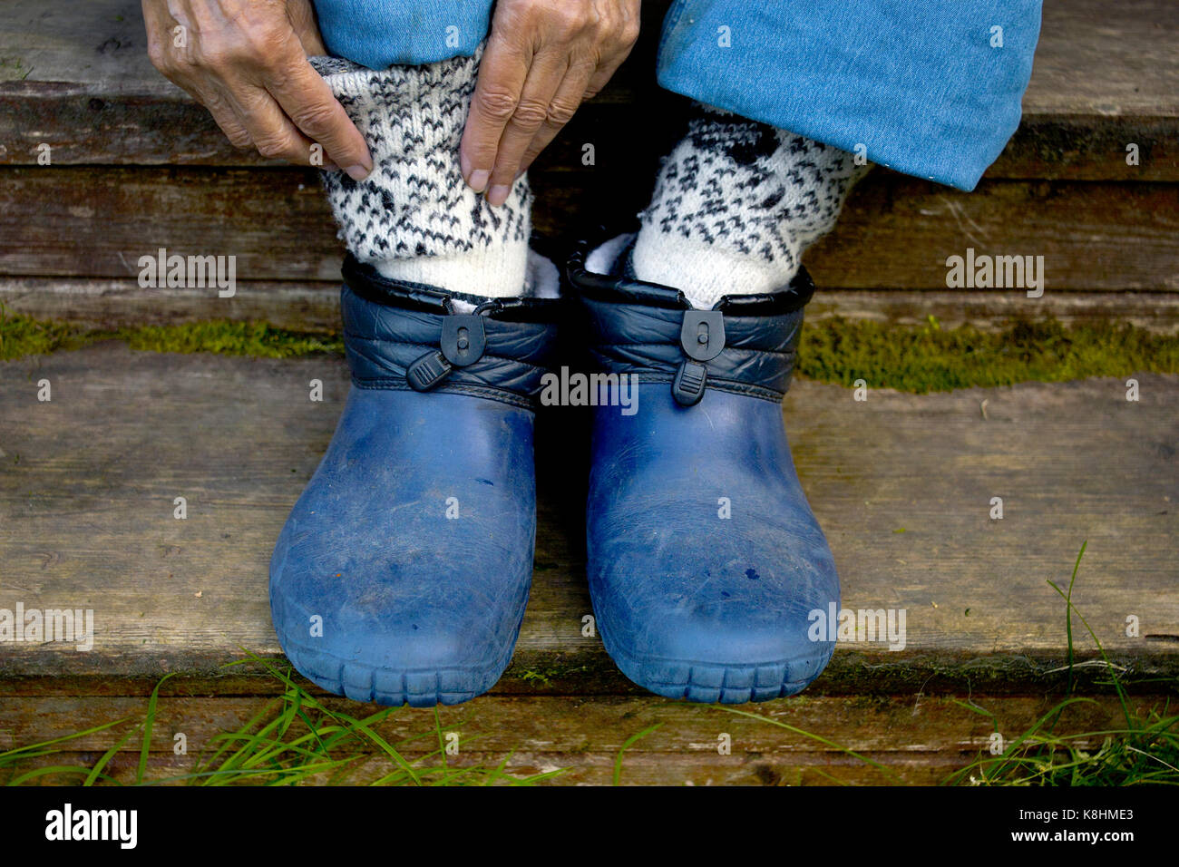 Femme de mettre des chaussettes chaudes tout en étant assis sur le marches de bois, gros plan photo recadrée Banque D'Images