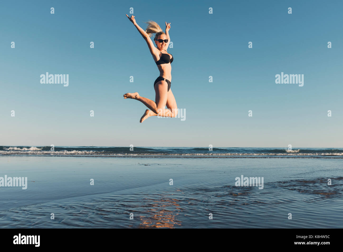 Carefree woman jumping at beach against clear sky Banque D'Images