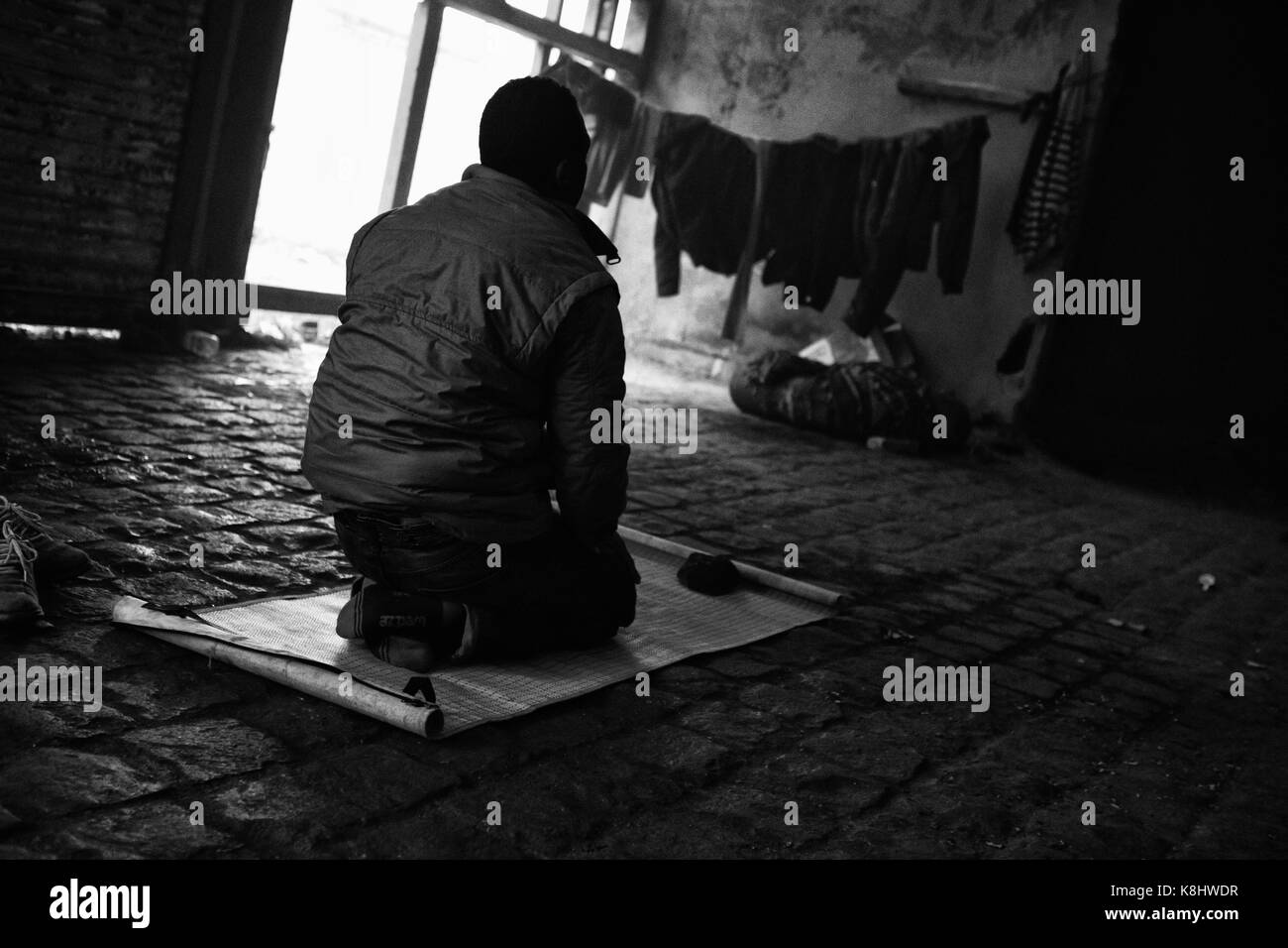 Un demandeur d'asile soudanais prie vers La Mecque dans un entrepôt désaffecté, illégale appelée "Africa House" à Calais, France le 18 mars 2010. Asyl africains Banque D'Images