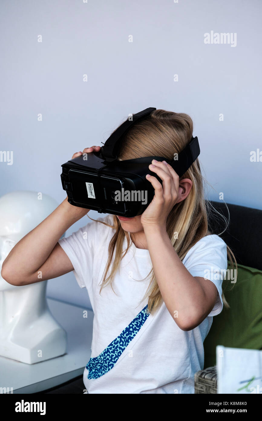 Jeune fille portant le casque Oculus Gear VR, équipement de réalité virtuelle métaverse (VR) avec téléphone Samsung. Banque D'Images