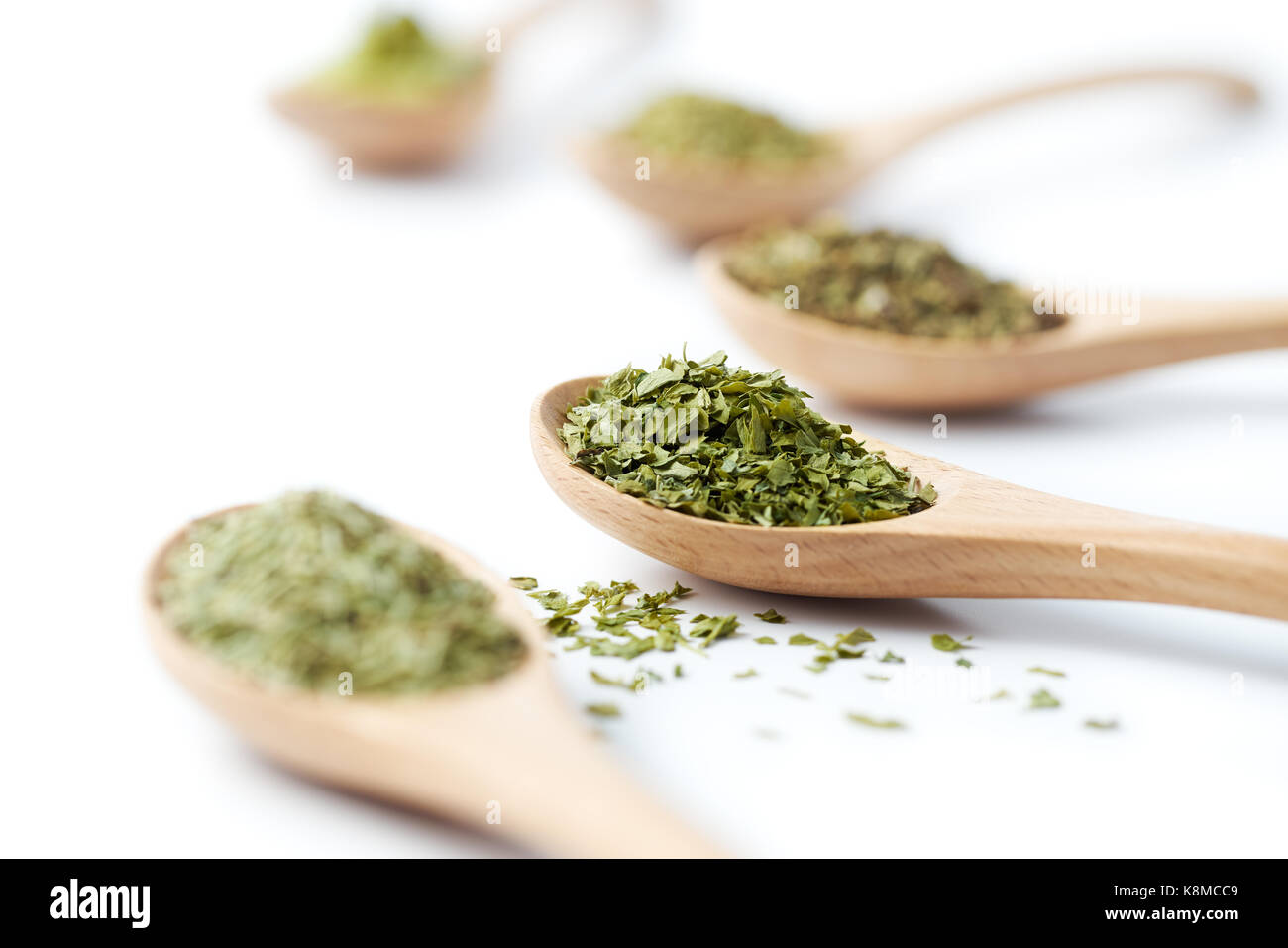 Cuillère en bois rempli d'herbes séchées sur fond blanc Banque D'Images